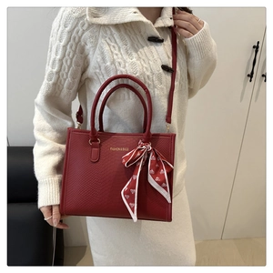 Détail du sac à main rouge gaufré avec texture serpent et ruban en soie à motif cœurs