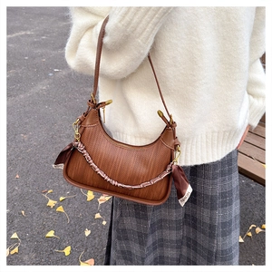 Detail of caramel brown woven hobo bag with fashion silk scarf on a model