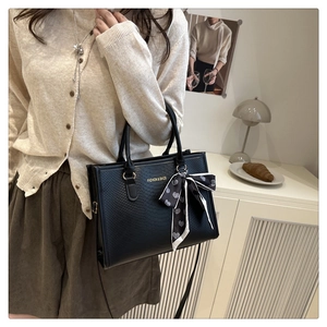 Détail du sac cabas noir gaufré avec ruban à cœurs et bandoulière en cuir souple