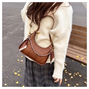 Macro view of woven textured brown hobo bag with a decorative FASHION ribbon accent
