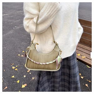 Detailed close-up of olive green woven crescent bag with silk scarf on the handle