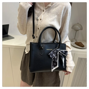 Détail du sac cabas noir avec texture serpent, texte mode et foulard à cœurs