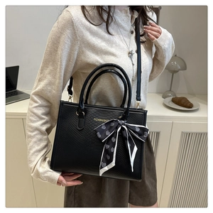 Détail du sac cabas noir en cuir gaufré avec un foulard en soie élégant sur l'anse