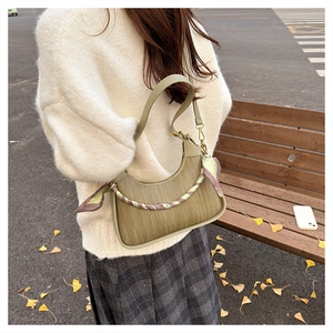 Detail of green Hobo shoulder bag with decorative silk scarf against autumn background