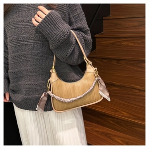 Straw hobo bag with leather trim and silk scarf detail on a wooden staircase