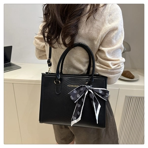 Détail d'un sac cabas noir à texture serpent avec un foulard en soie à motif de cœur