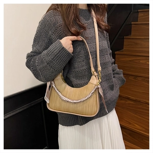 Detail of a woven straw handbag with geometric silk scarf and faux leather shoulder strap