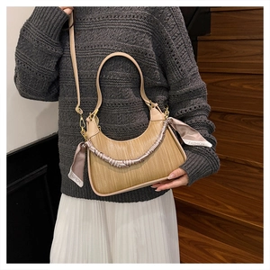 Close-up of woven hobo bag with a decorative fashion scarf and golden hardware detail