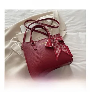 Détail du sac cabas rouge à motif serpent avec foulard en soie et lettrage doré