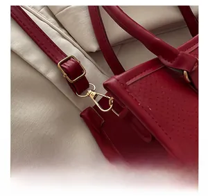 Gros plan des détails dorés et de la boucle sur le sac à main en cuir grainé rouge