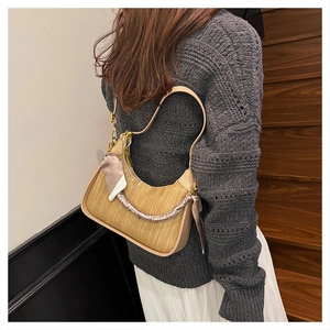 Detailed shot of khaki woven handbag with silk scarf handle and leather splicing details