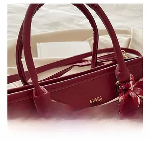 Détail du sac cabas bordeaux texturé avec foulard élégant et logo doré en relief