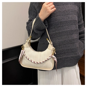 Detail of cream woven shoulder bag featuring an elegant red and white striped silk scarf
