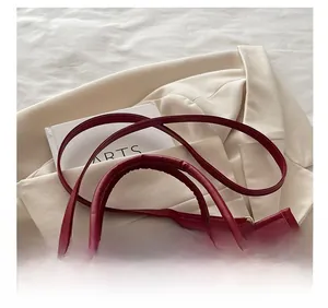 Détail du sac cabas bordeaux avec texture gaufrée et foulard décoratif en soie à cœurs