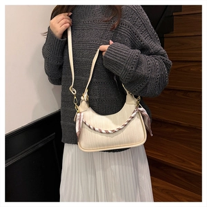 Close-up of beige woven hobo bag with red striped silk scarf on model