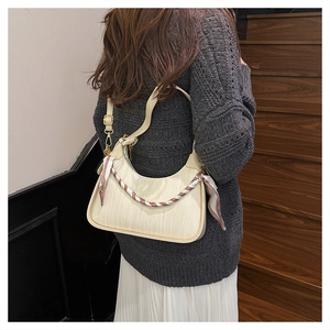 Detail of off-white woven hobo bag featuring a decorative striped silk scarf and gold hardware
