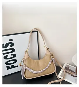 Detail of beige half-moon bag with woven leather texture and silk scarf wrapped chain