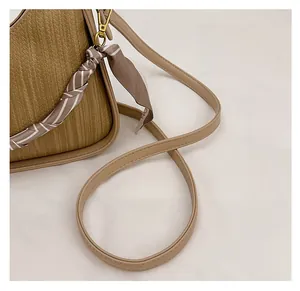 Detail of woven texture handbag with beige leather strap and gold metal buckle