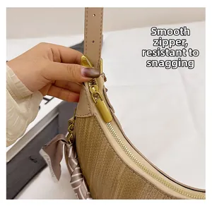 Close-up of smooth gold zipper on woven crescent bag with decorative silk scarf