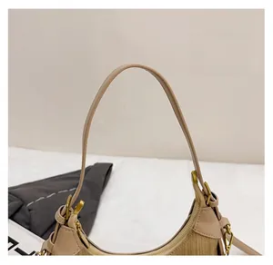 Detail of slim beige handle and metallic zipper on a woven crossbody shoulder bag