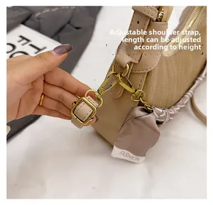 Detail of adjustable leather strap and golden metal buckle on beige crossbody bag