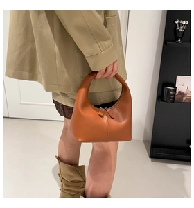 Brown leather crescent handbag styled with a khaki suit in a modern interior setting