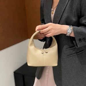 Minimalist beige half-moon bucket bag with vertical stitching shown in a fashion setting