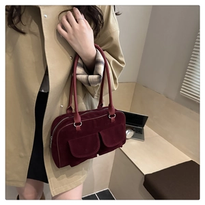 Detailed close-up of dark red vintage shoulder bag with suede texture and dual front pockets