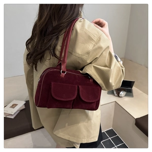 Détail du sac fourre-tout en daim bordeaux avec doubles poches porté à l'épaule