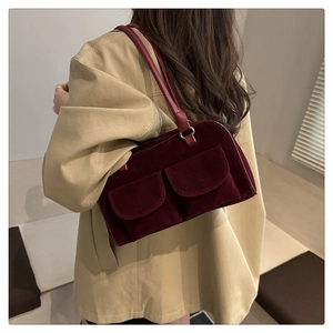 Detail of dark red velvet shoulder bag showing flap pockets and slender strap on model