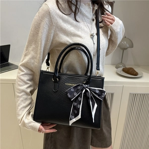 Sac fourre-tout noir gaufré avec foulard coeur et lettrage doré dans un décor cosy