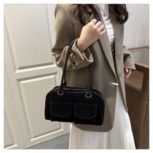 Detail of a black suede hobo bag with two front flap pockets and leather handles