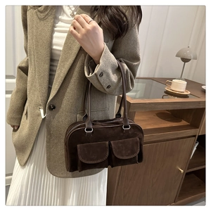 Detail of vintage dark brown suede shoulder bag with two front flap pockets and slim handles
