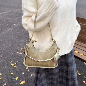 Chic beige woven shoulder bag with silk scarf handle and crescent shape in autumn setting