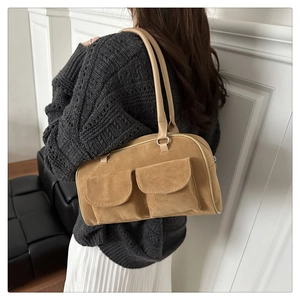 Detailed view of khaki suede pillow bag with dual front pockets worn on shoulder