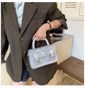 Close-up of snakeskin embossed texture and gold hardware on a luxury office handbag