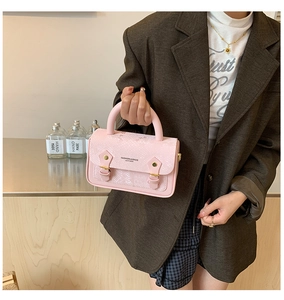 Detail of pink snake skin pattern handbag with metal clasp and gold embossed fashion logo