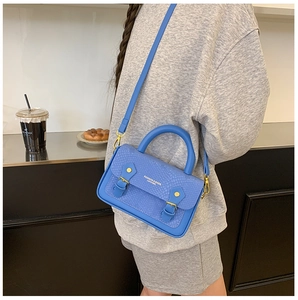 Close-up of blue snakeskin pattern texture and gold buckle detail on crossbody bag