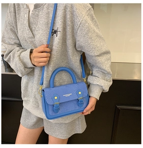 Detail of blue snake pattern mini crossbody bag with golden metal hardware and twin straps