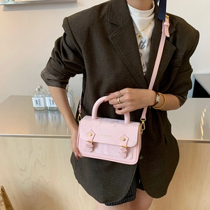 Pink snake pattern crossbody bag with gold buckles shown on a female model with a blazer