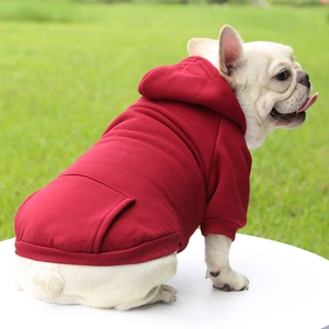 French Bulldog modeling a red hooded pet sweatshirt with back pocket on a green lawn