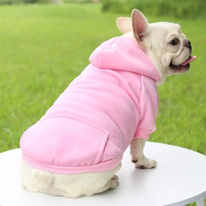 Pink hooded pet sweatshirt with back pocket on a French Bulldog sitting outdoors