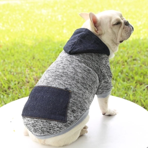 Detail of gray pet hoodie featuring a dark blue denim pocket and rib-knit cuffs on grass