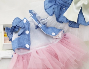 Detail of pink ruffled mesh skirt and blue denim vest with a cute green satin bow