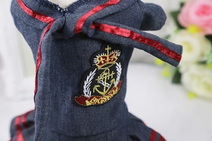 Detail of dog denim dress featuring a red satin bow and British nautical crown embroidery