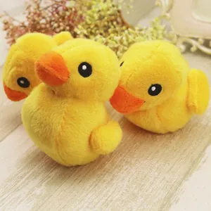 Three cute yellow plush duck dog toys with squeakers on a light wooden background