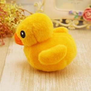 Cute yellow plush squeaky duck pet toy for dogs and cats on a warm wooden background