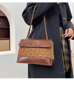 Close-up of brown suede crossbody bag featuring diamond quilting and gold chain strap