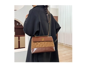 Detail of retro quilted brown shoulder bag with gold chain and circular metal lock