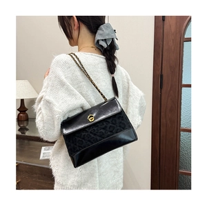 Detailed shot of black quilted shoulder bag with gold twist lock and chain strap